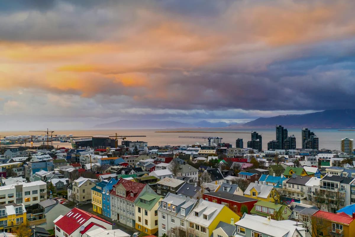Aerial view of Reykjavik, Iceland, showcasing colorful houses and a stunning sunset over the city.