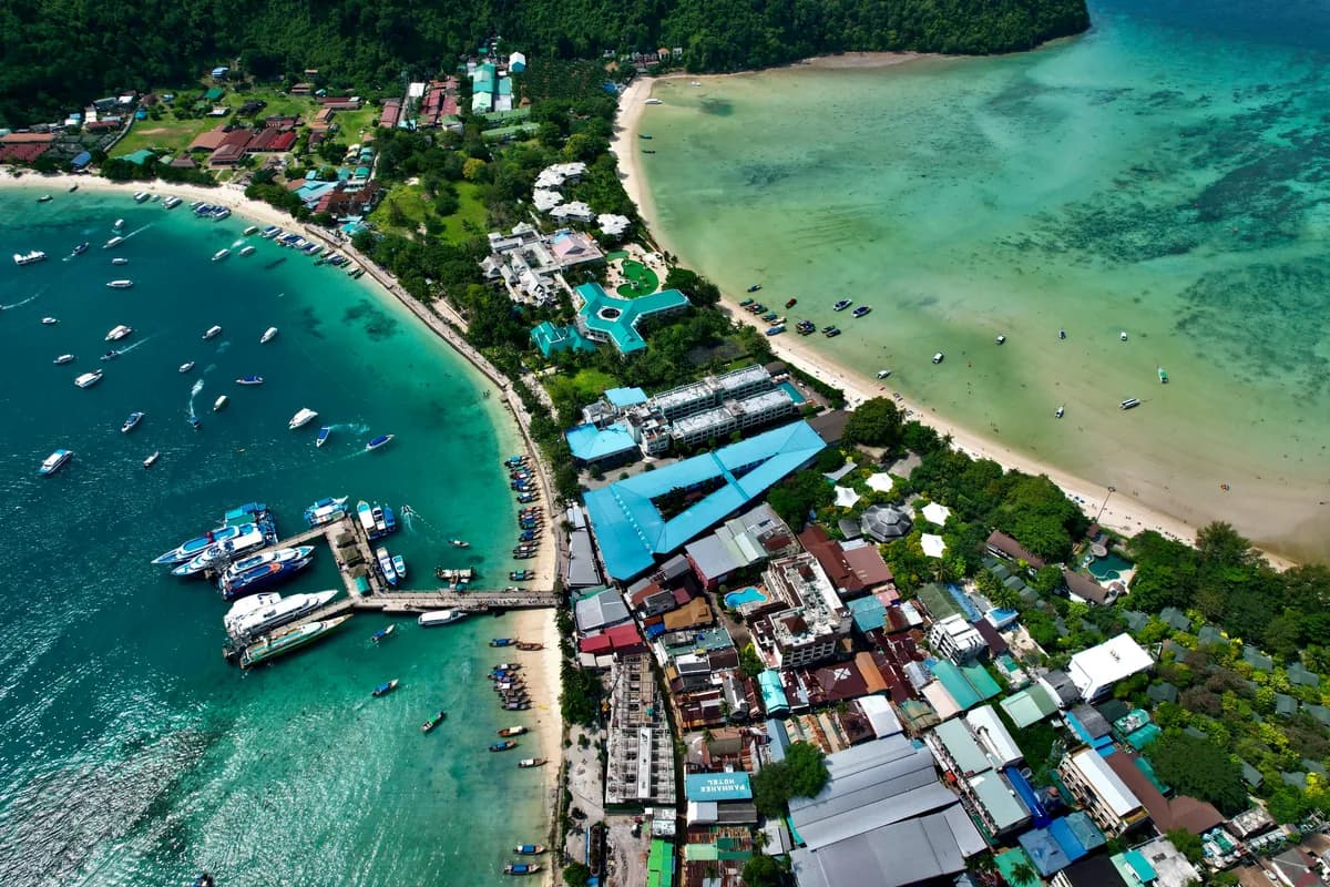 Dramatic aerial view of Ton Sai Village with vibrant sea and lush greenery on Koh Phi Phi, Thailand.