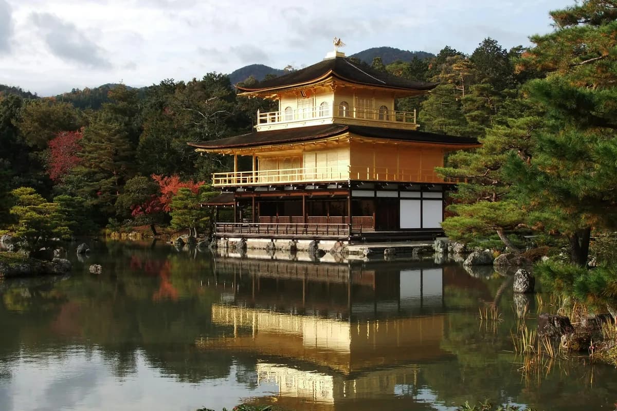 Kinkaku-ji (Golden Pavilion) reflecting in a serene pond surrounded by lush greenery in Kyoto, Japan.