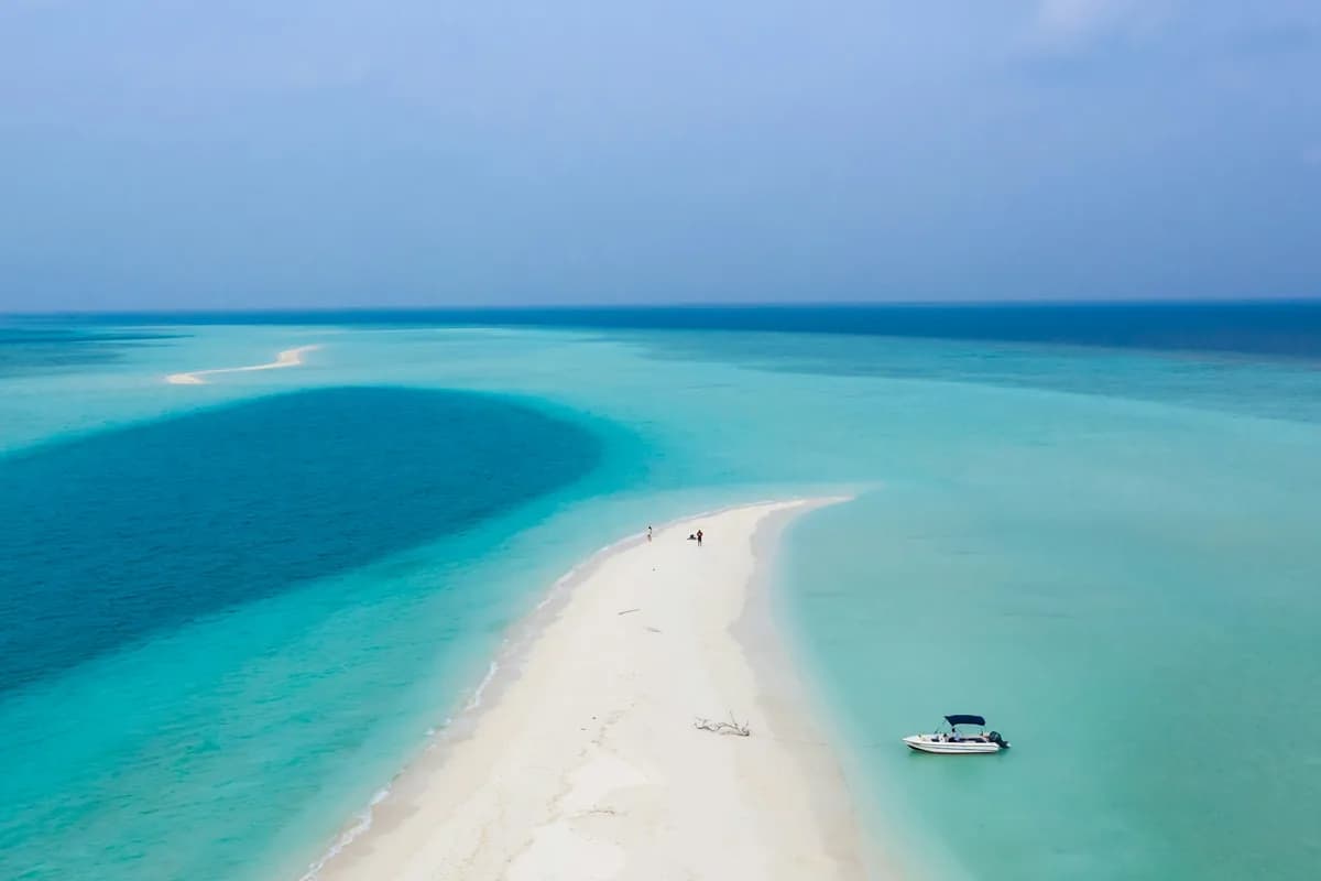A traditional dhoni boat on the calm turquoise water of a Maldivian atoll