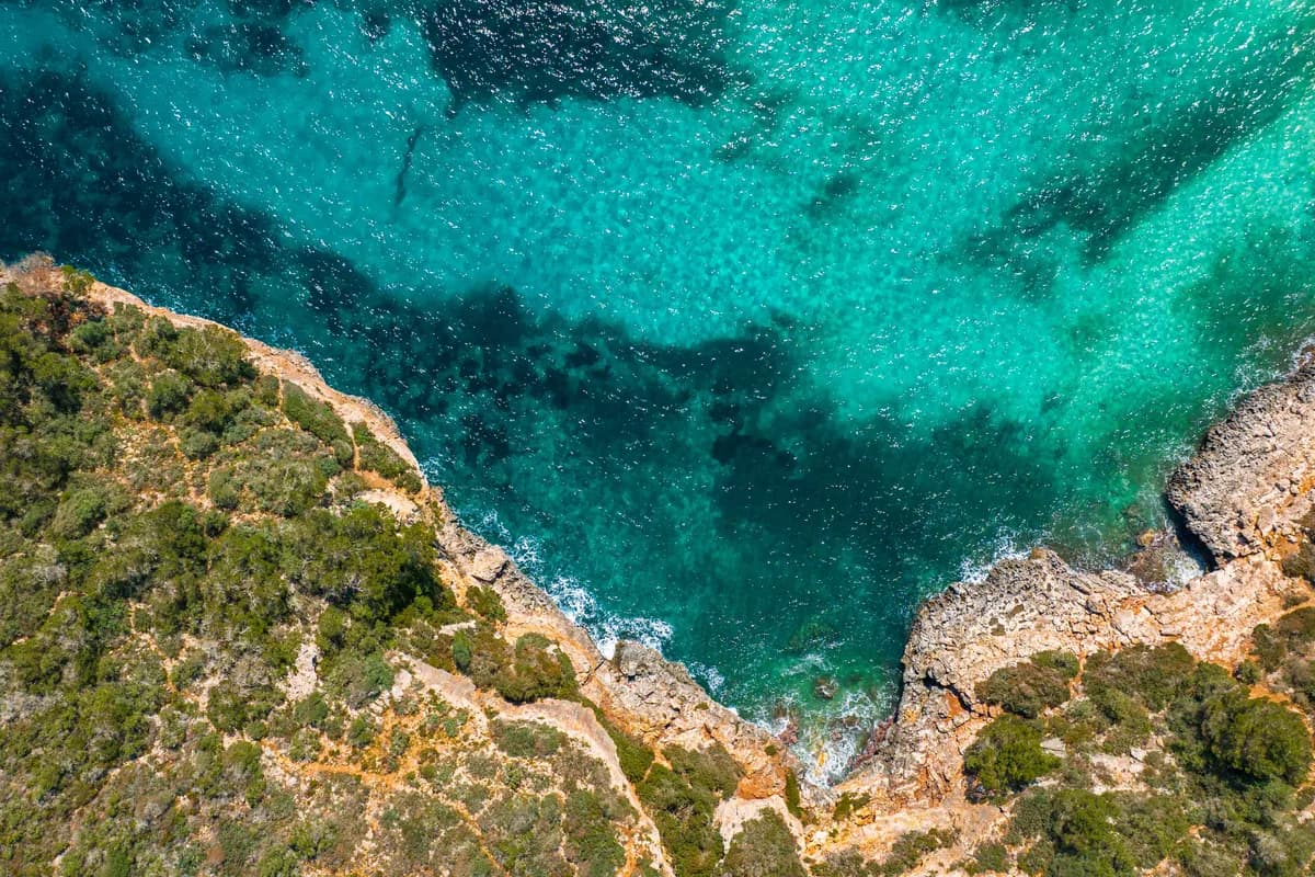 Stunning aerial view of rocky cliffs and clear turquoise sea in Mallorca, perfect for travel inspiration.