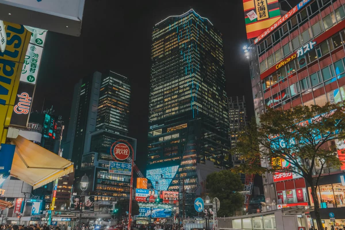Night scene of Tokyo with illuminated neon skyscrapers and bustling street life, showcasing vibrant city energy.