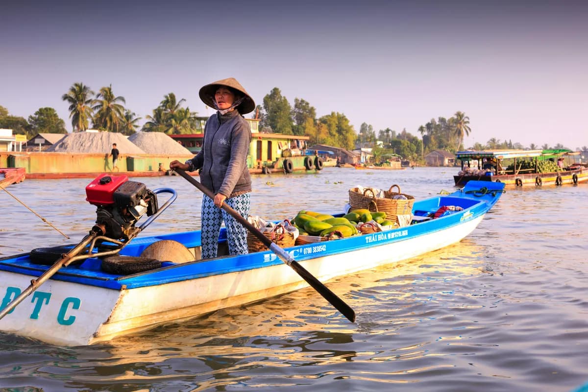 Woman steering a motorized boat filled with goods on the Mekong Delta in vibrant riverine Vietnam.