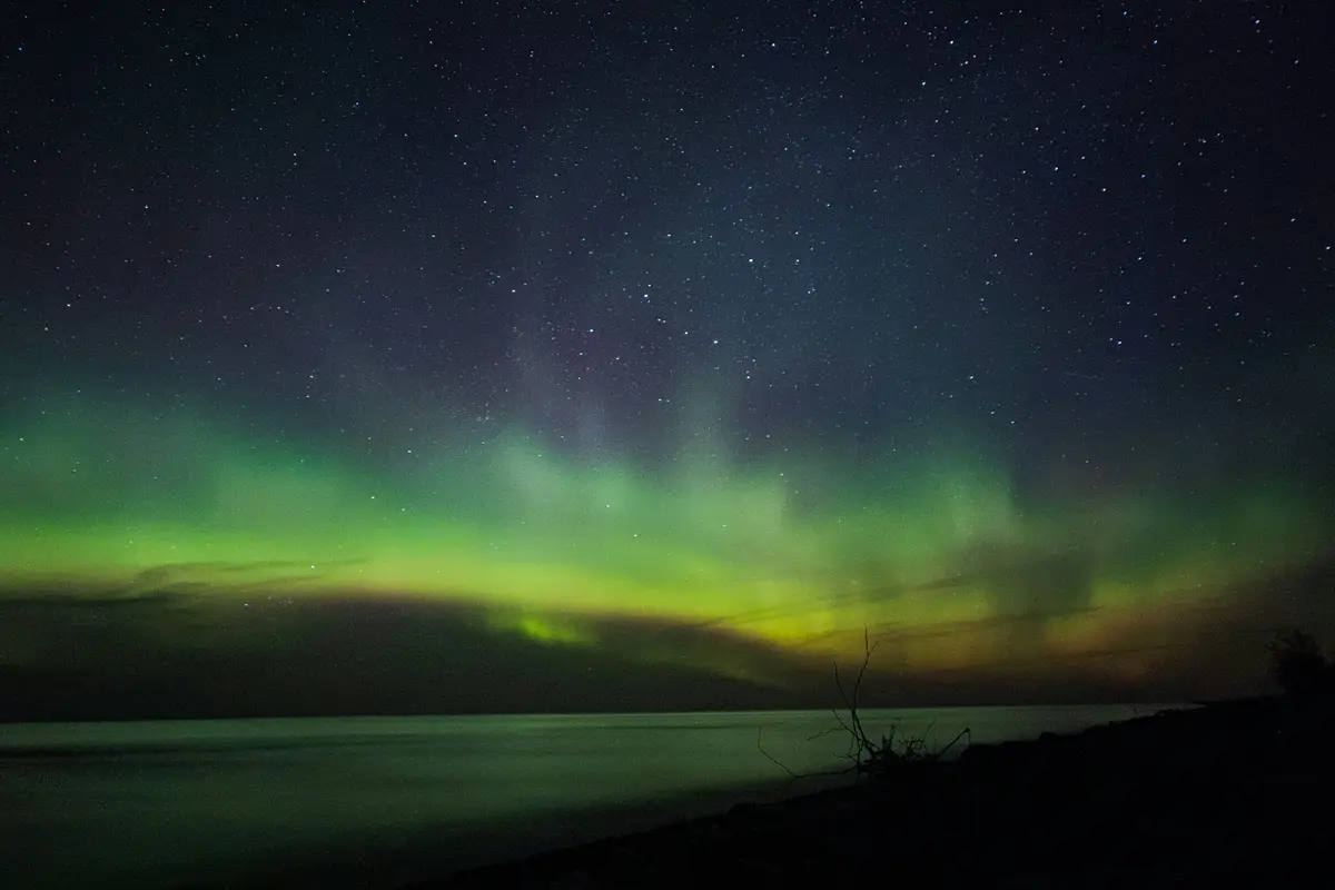 Green aurora over Lake Superior seen from a dark Michigan shoreline
