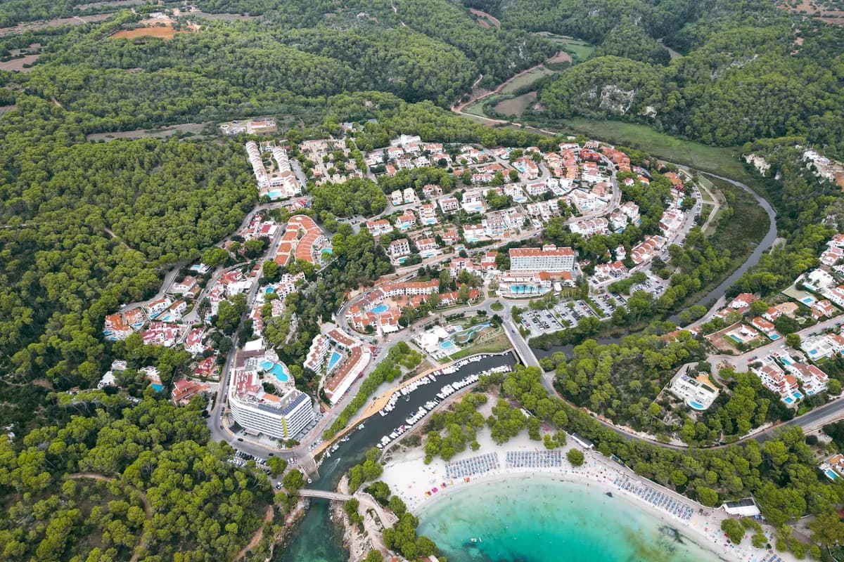 Stunning aerial view of Cala Galdana's beautiful beach and lush landscape in Spain, perfect for travel and adventure enthusiasts.