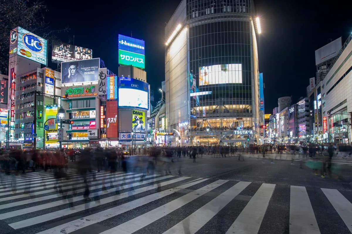 Experience the vibrant energy of Shibuya Crossing in Tokyo at night with bustling crowds and colorful neon lights.