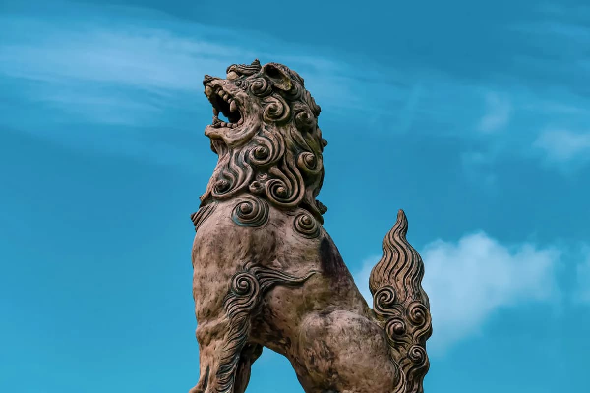 Majestic Shisa guardian-lion statue with intricate design set against a vibrant blue Okinawan sky.