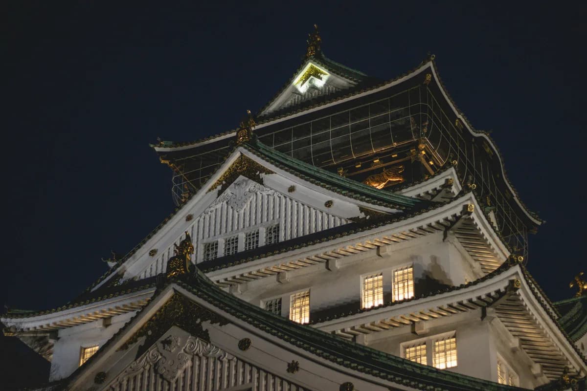 Stunning night view of Osaka Castle illuminated against the night sky, showcasing traditional Japanese architecture.