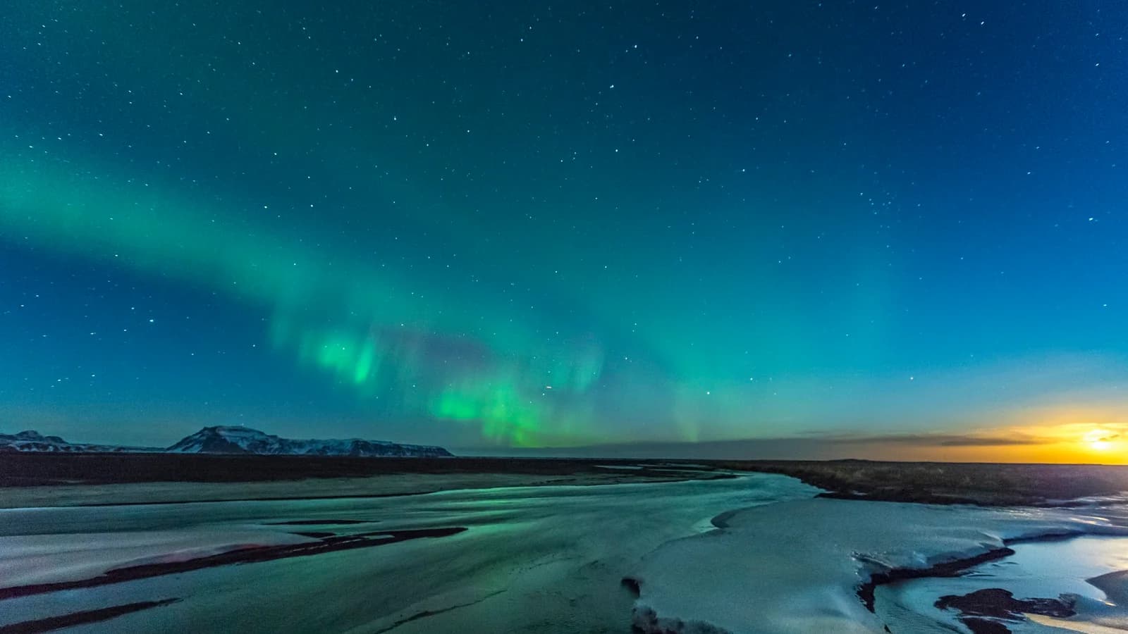 Aurora borealis over Iceland — vibrant green and blue lights dancing across a star-filled night sky