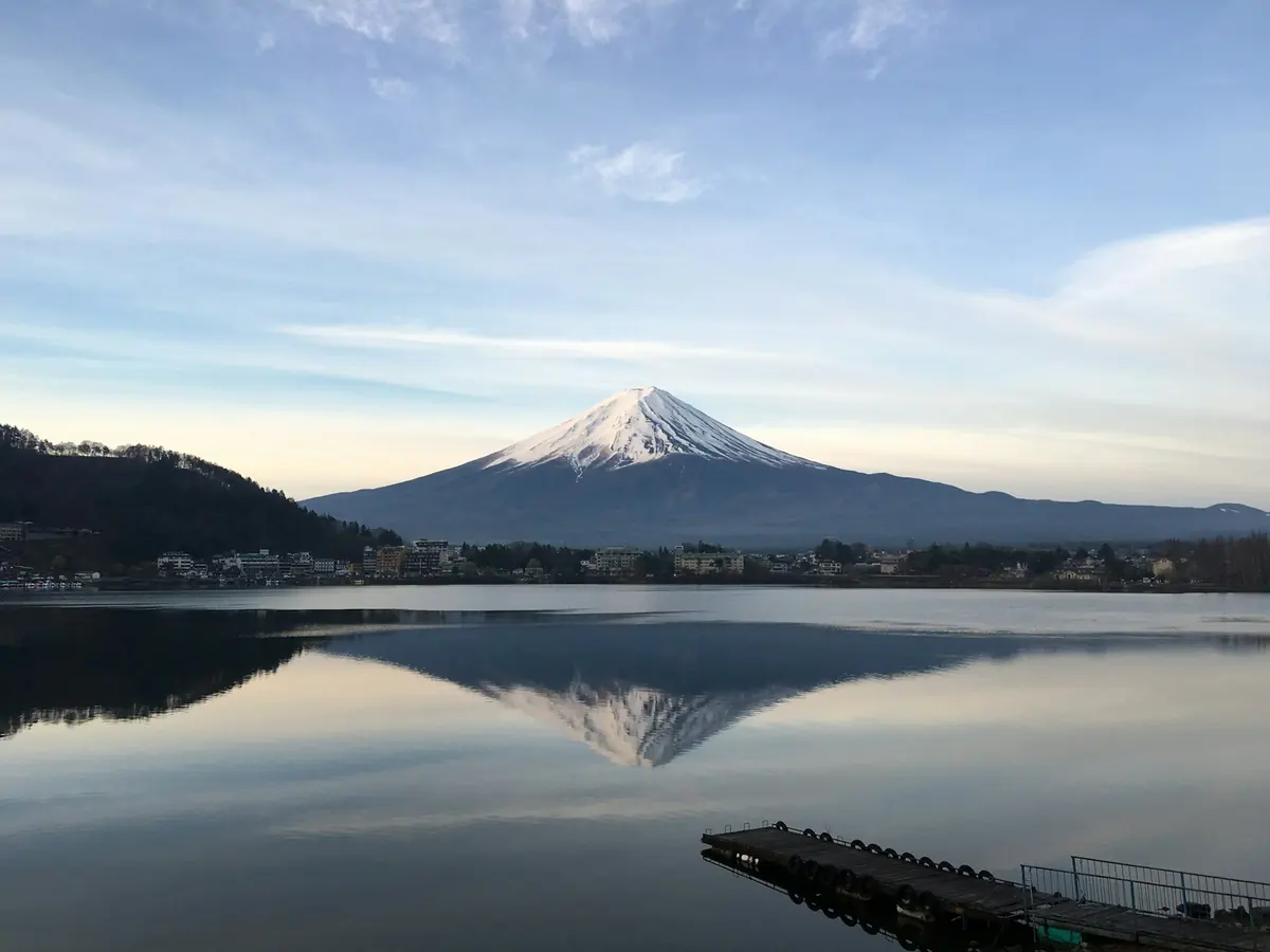 Mount Fuji reflected in a calm Lake Kawaguchi under a pale morning sky