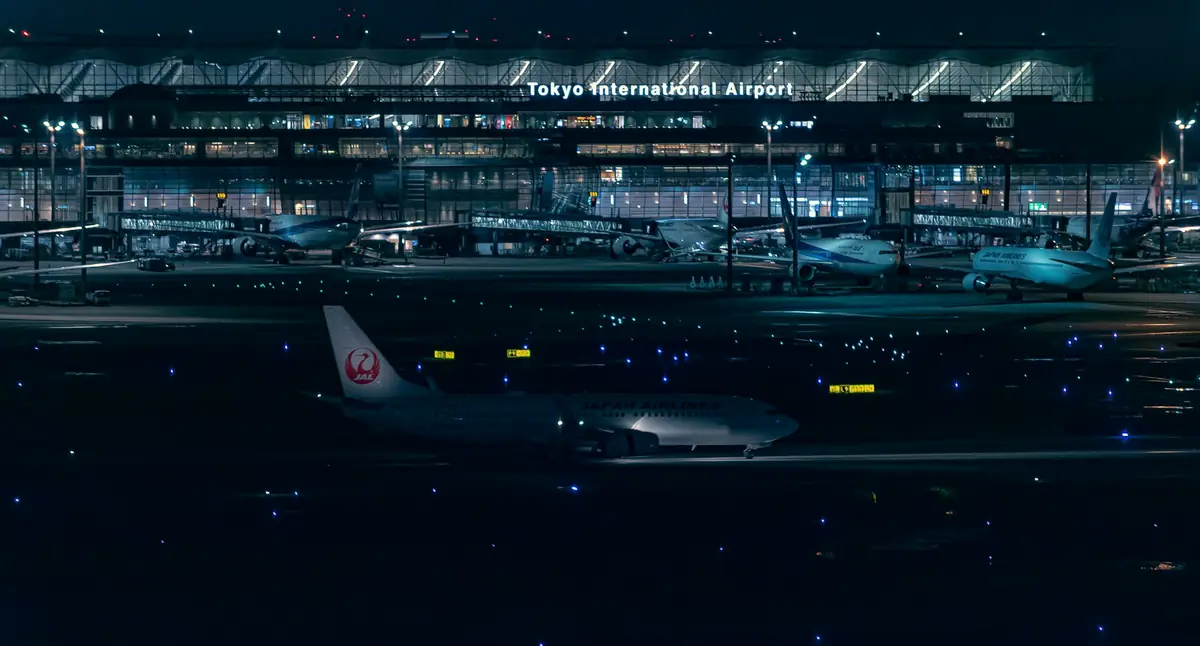 Haneda Airport terminal lit up at night with planes at the gates